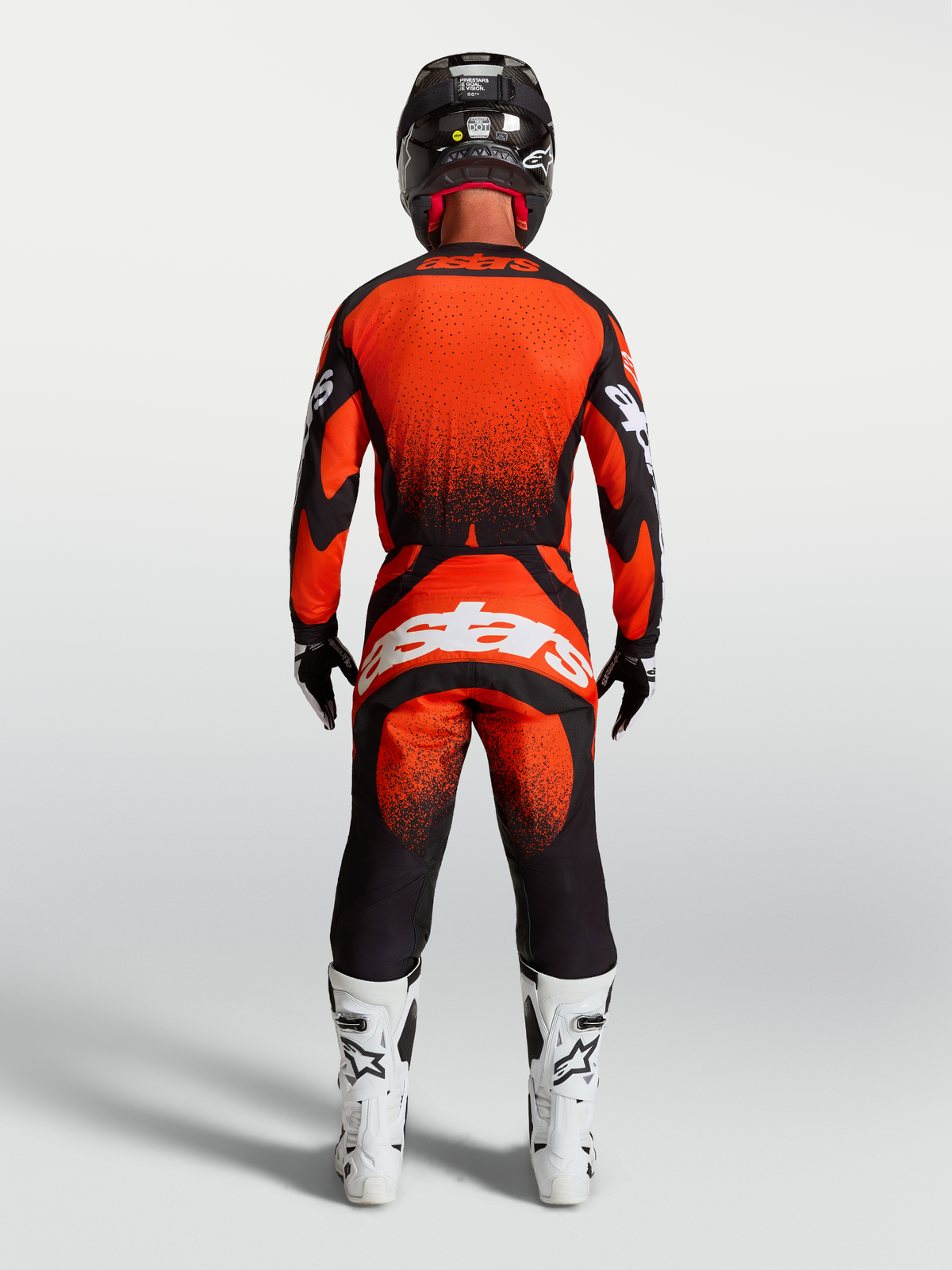 Alpinestars Maillot Techstar Swan et Techstar Swan Gear Set, tenue de motocross pour homme, rouge cardinal et noire, vue de dos montrant la coupe athlétique et les graphismes, avec bottes de moto blanches.