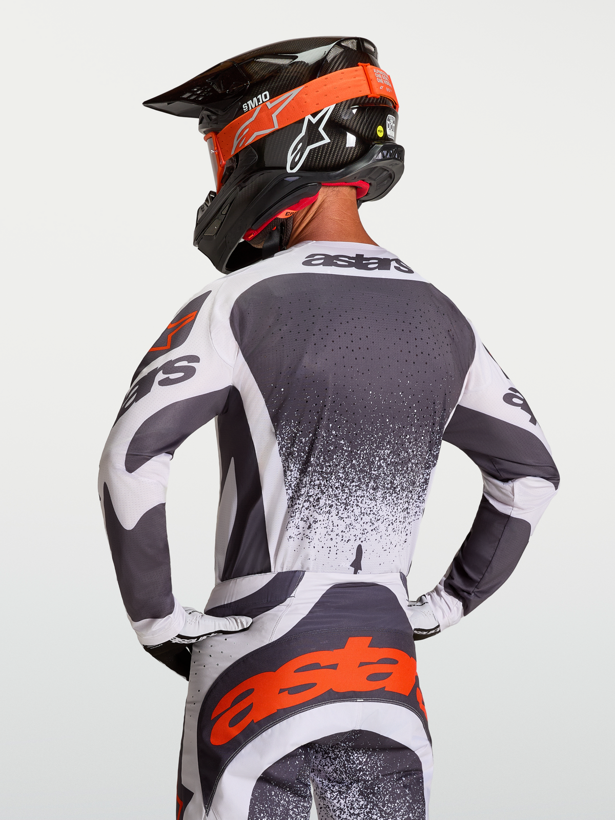 Maillot Alpinestars Techstar Swan, maillot de motocross gris et blanc avec détails rouges, perforations laser, porté par un pilote.
