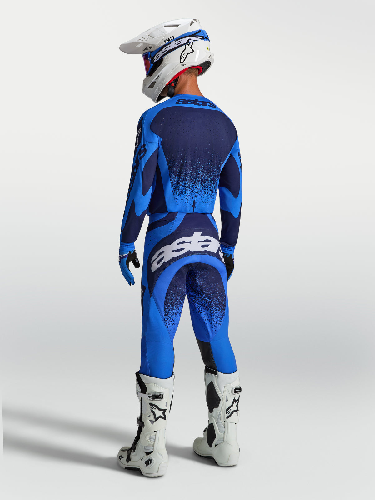 Alpinestars Techstar Swan, ensemble de motocross bleu et bleu foncé, coupe athlétique, bottes et casque blancs.