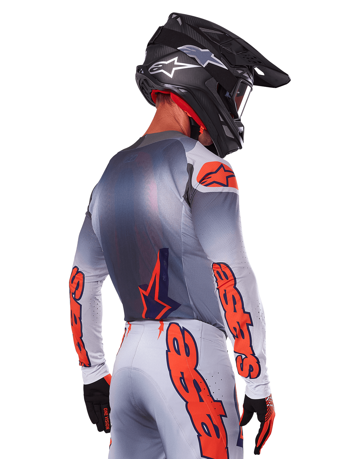 Motocross-Fahrer von hinten im Alpinestars 2025 Supertech Lipan Trikot und Ausrüstungsset, Grau mit Orange Fluo Akzenten, markantes Branding auf Rücken und Ärmeln, schwarzer Helm und schwarze Handschuhe, koordiniertes Motocross-Rennoutfit