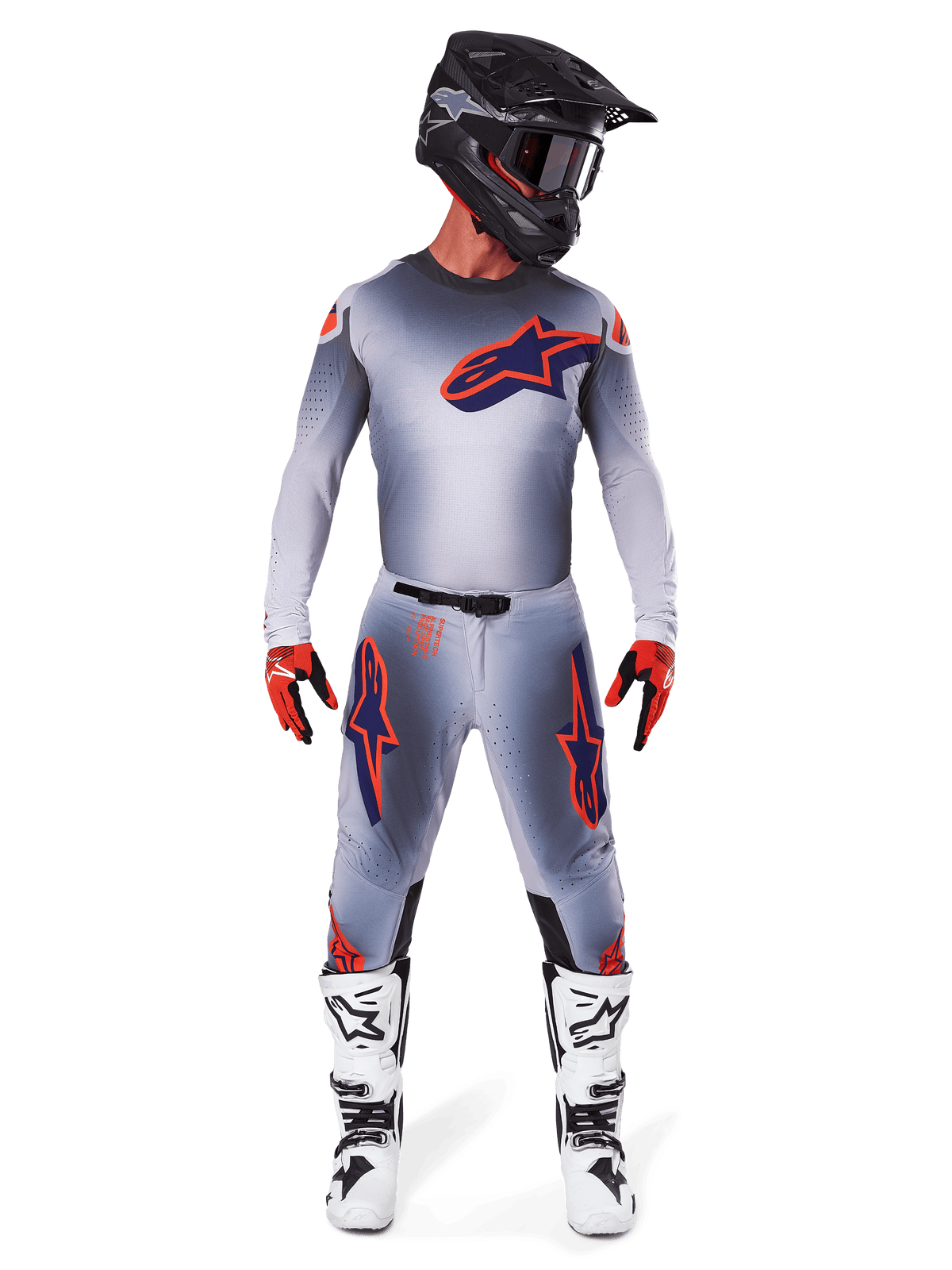 Motocross-Fahrer im 2025 Supertech Lipan Ausrüstungsset in Grau Orange Fluo, graues Trikot mit orangefarbenen Akzenten und navyblauem Alpinestars-Logo, passende graue Hose mit großen Logos an den Oberschenkeln, mattschwarzer Helm, weiß-schwarze Stiefel und rot-schwarze Handschuhe, komplette Profi-Rennausrüstung.