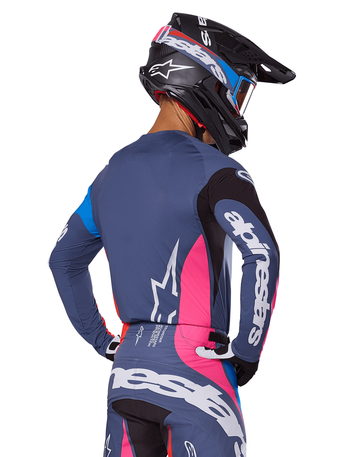 Motocross-Fahrer in der Rückansicht mit dem Alpinestars 2025 Techstar Dreem Ausrüstungsset in Grau, blaugraues Trikot und Hose mit pinken und schwarzen Einsätzen, weiße Alpinestars-Logos auf den Ärmeln und dem Rücken, passender schwarzer Helm mit blau-pinken Grafiken.