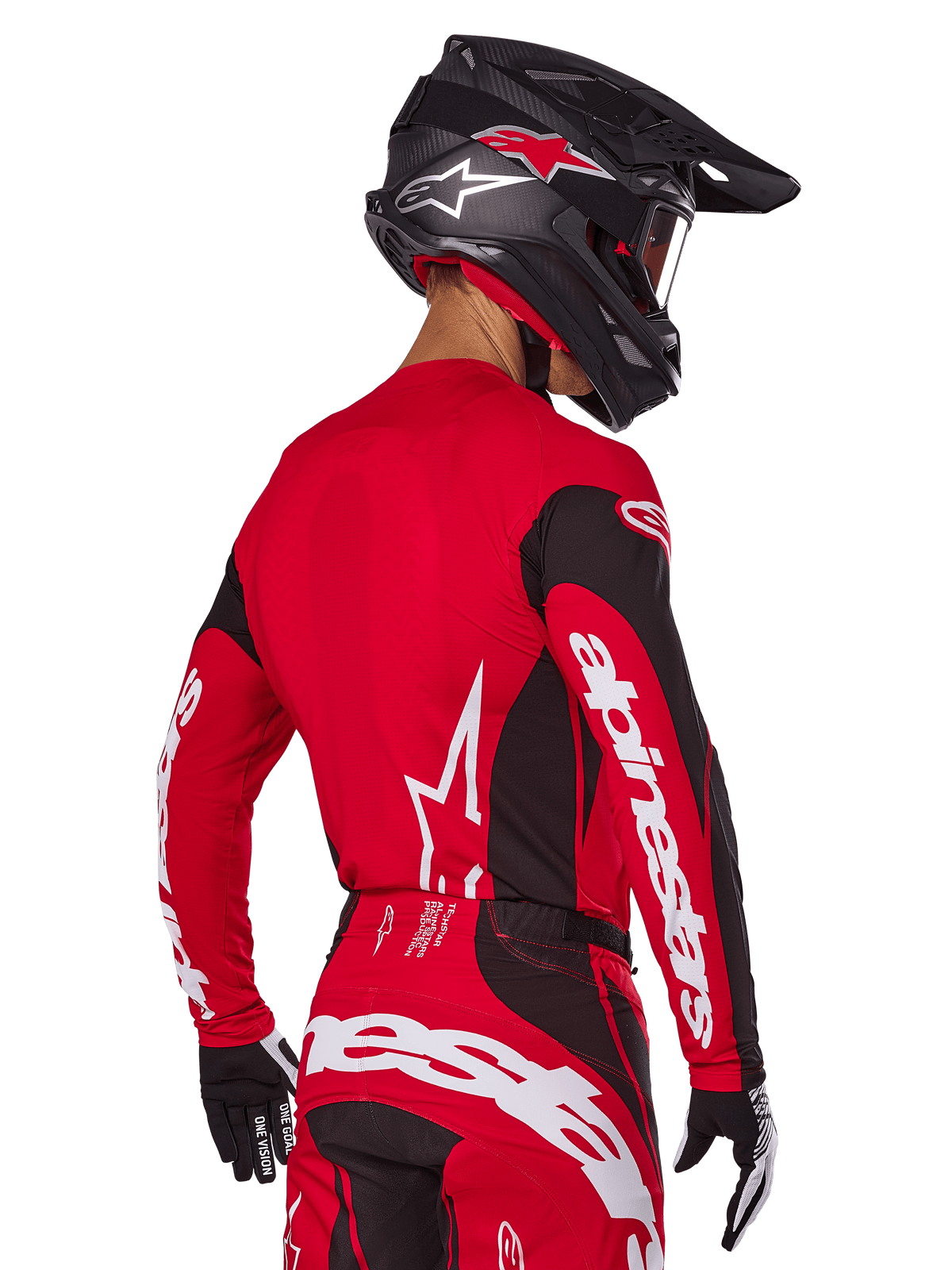 Motorcrosser van achteren gezien in Alpinestars 2025 Techstar Dreem gearset, rood en zwart jersey met witte merknaam op de mouwen, bijpassende rood-zwarte broek met opvallend wit logo op het zitvlak, zwarte carbon helm met rode accenten, zwart-witte handschoenen, professionele off-road outfit.