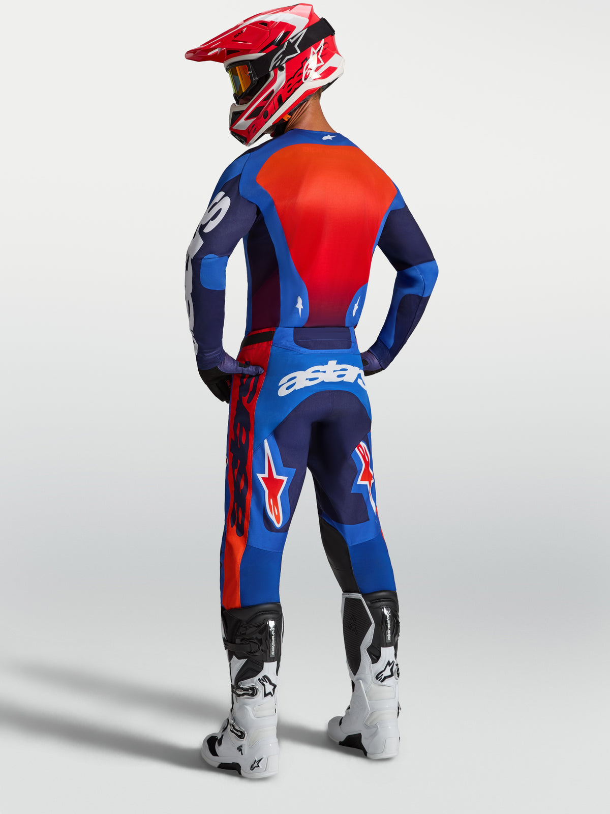 Alpinestars Racer Hunt jersey, heren-motocrossuitrusting, blauw en rood, vochtafvoerend polyfabric, achterzijde van model met volledige off-road uitrusting en witte laarzen