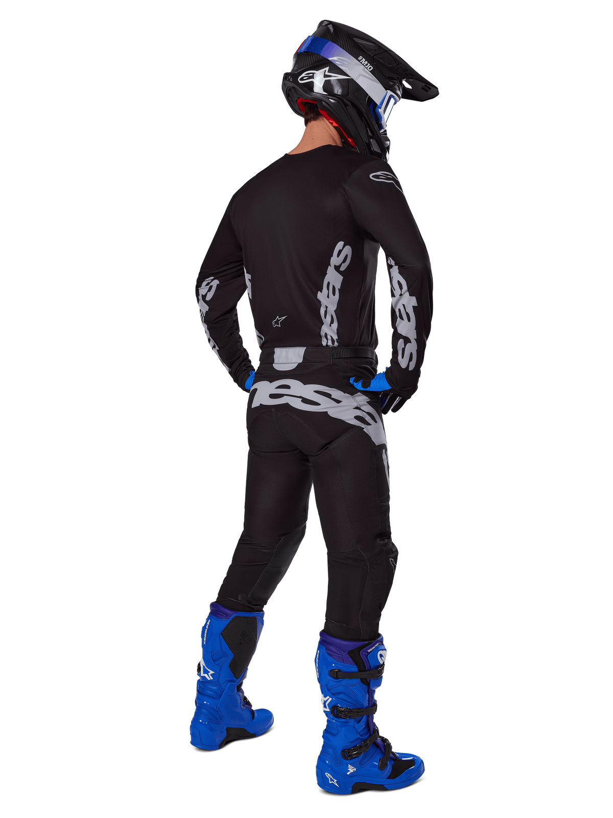 Motocross-Fahrer in der Rückansicht trägt das Alpinestars 2025 Racer Graphite Gear Set, schwarz-graues Trikot und Hose mit grauem Branding, kombiniert mit leuchtend blauen Motocross-Stiefeln, einem schwarz-blauen Helm und blauen Handschuhen, komplettes Performance-Offroad-Outfit.