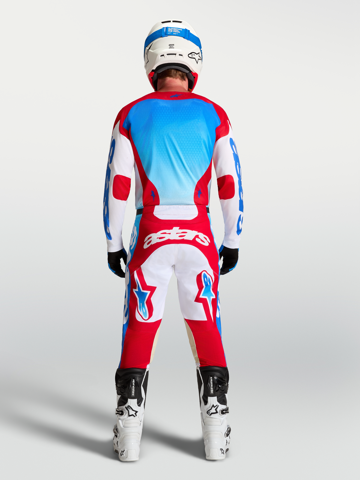 Alpinestars Racer Hunt, pantalons et ensemble de motocross rouge, blanc et bleu, vue de dos sur mannequin.