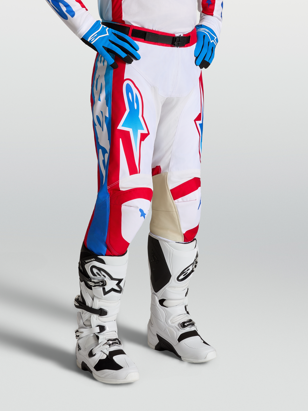 Alpinestars Pantalons Racer Hunt, pantalons de motocross homme, blancs, rouges et bleus, construction pré-courbée avec genoux intérieurs en cuir, portés avec des bottes de moto blanches