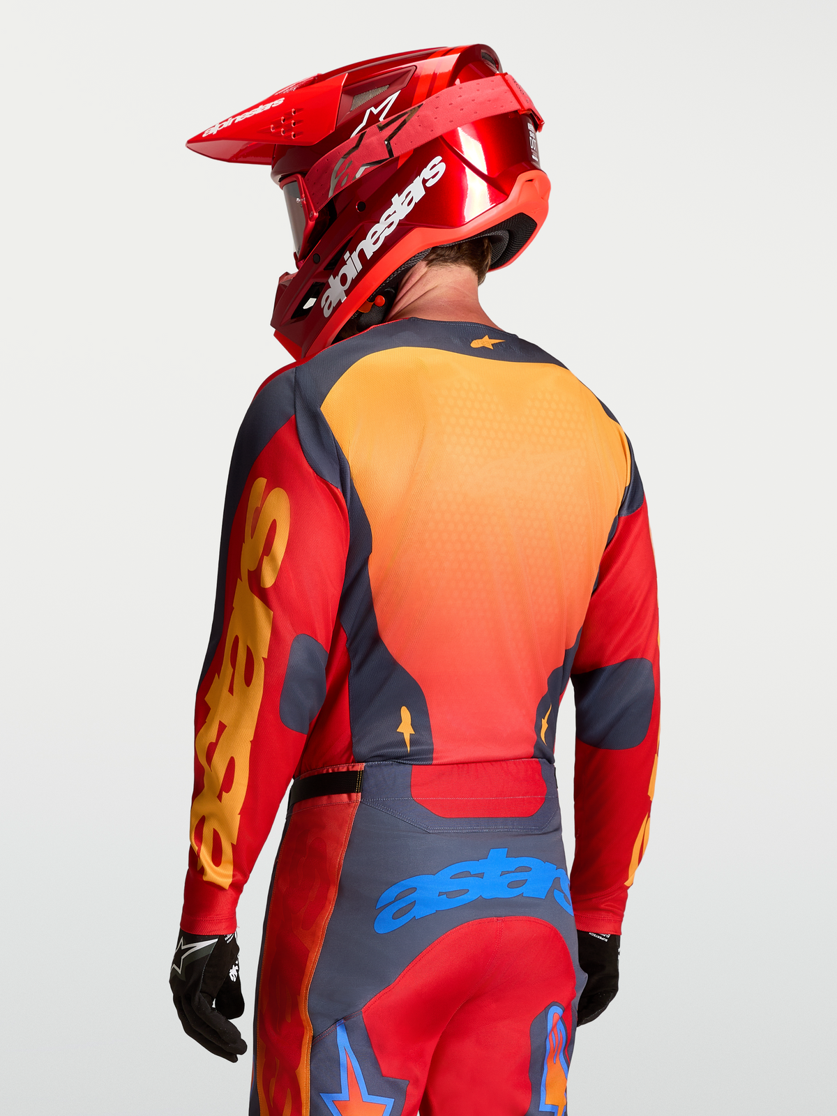 Maillot Racer Hunt Alpinestars, haut de motocross pour homme, rouge feu et gris avec panneaux en maille orange, vue de dos montrant le textile technique respirant évacuant l'humidité