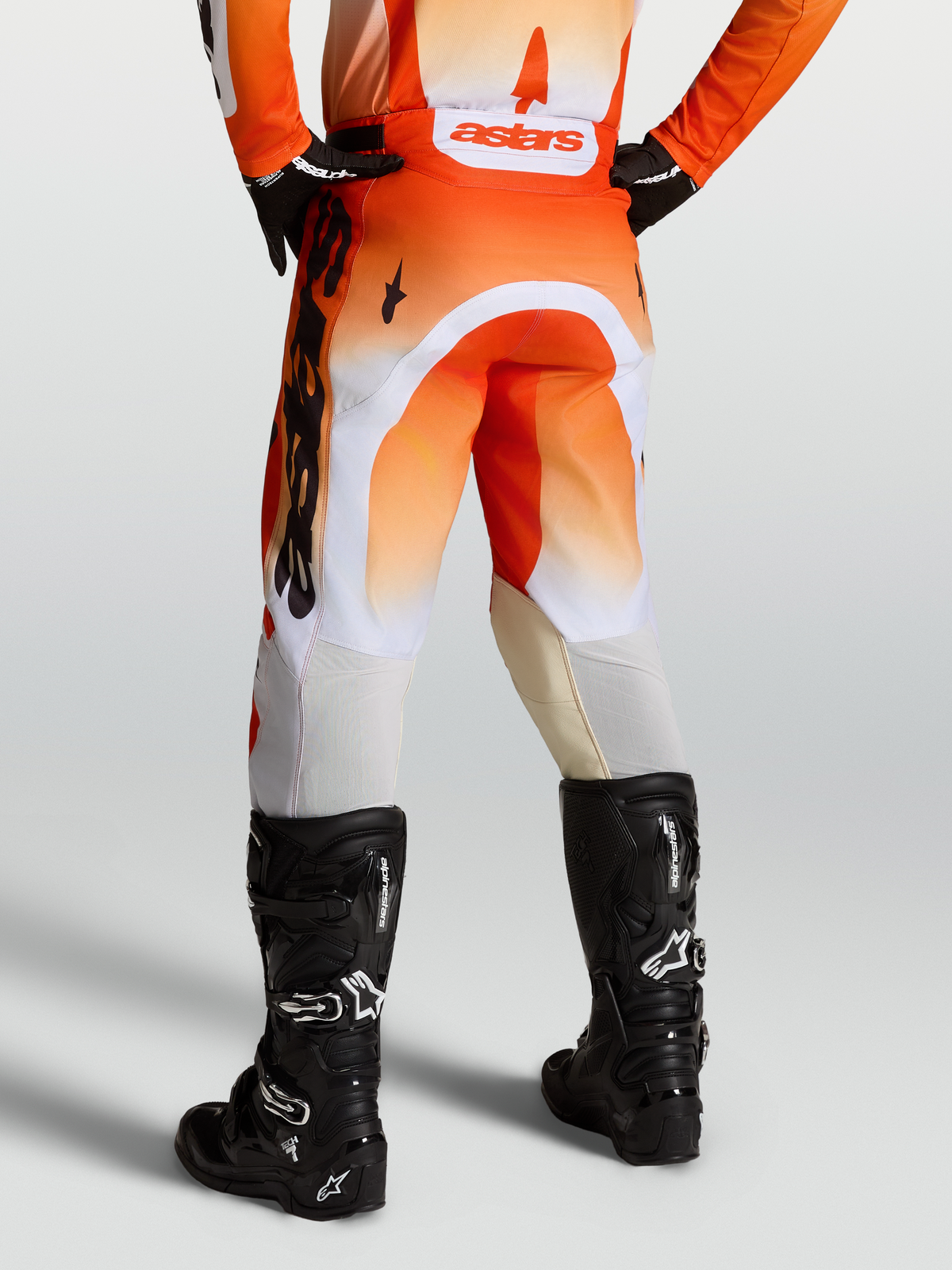 Pantalon Racer Amber Alpinestars, pantalon de motocross pour homme, rouge et blanc avec bottes noires, coupe préformée et tissu technique durable.