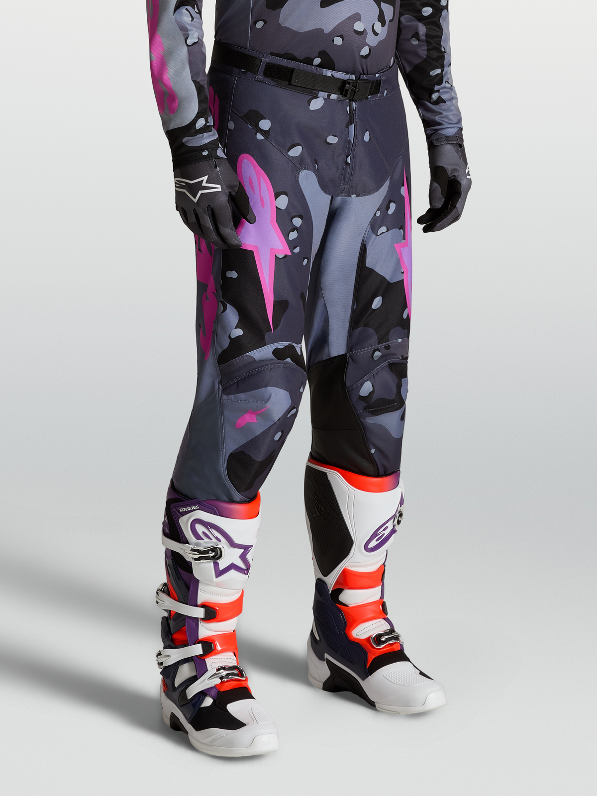Alpinestars Racer Lone Hose für Herren, Motocross-Hose im Grau-Camo-Design mit Pinken Akzenten, 600D Polyfabric-Konstruktion, getragen mit passenden Trikot und Tech 10 Stiefeln für Offroad-Performance.
