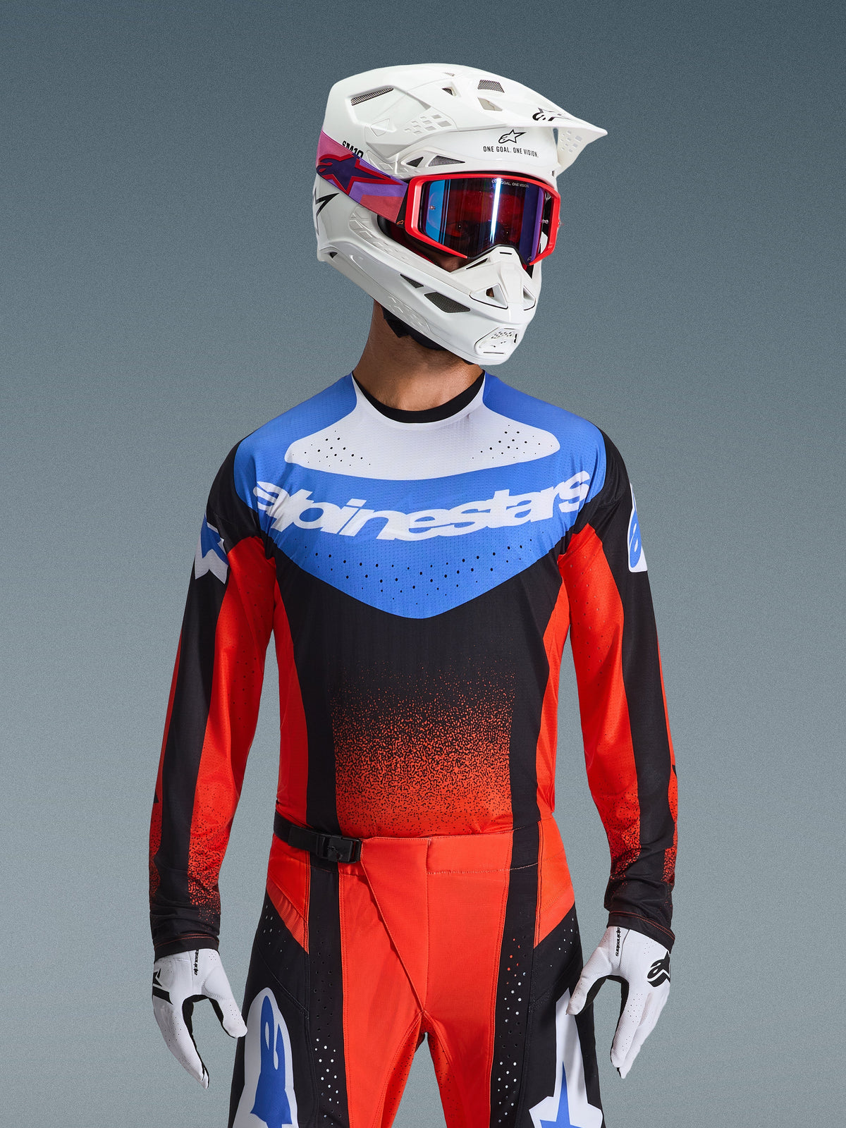 Ensemble d'équipement Alpinestars Techstar Knif 2026, tenue de motocross comprenant un maillot bleu, blanc, noir et rouge avec logo Alpinestars, pantalon assorti rouge et noir, porté avec un casque blanc, des lunettes rouges et des gants blancs, coupe athlétique haute performance pour la compétition tout-terrain