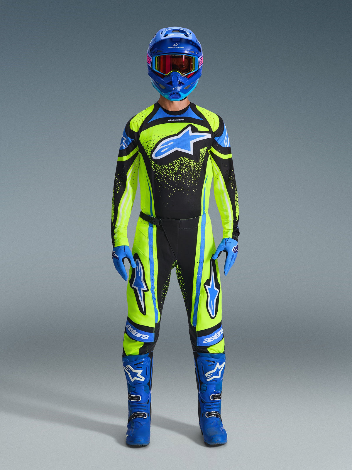 Motocross-Fahrer in kompletter Rennausrüstung, 2026 Techstar Nomur Trikot in Gelb Fluo und Dunkelblau, passende Motocross-Hose, blauer Helm mit rot getönter Brille, blaue Handschuhe und blaue Stiefel, koordiniertes Profi-Outfit für den Offroad-Rennsport