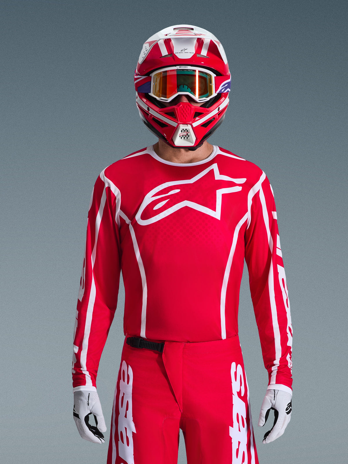 Motocross-Fahrer im kompletten Alpinestars 2026 Fluid Apex Gear Set, rotes Jersey mit großem weißem Stern-Logo auf der Brust, passende rote Hose mit weißem Branding, rot-weißer Helm mit irisierender Brille, weiß-schwarze Handschuhe, abgestimmtes rot-weißes Outfit für den Offroad-Rennsport