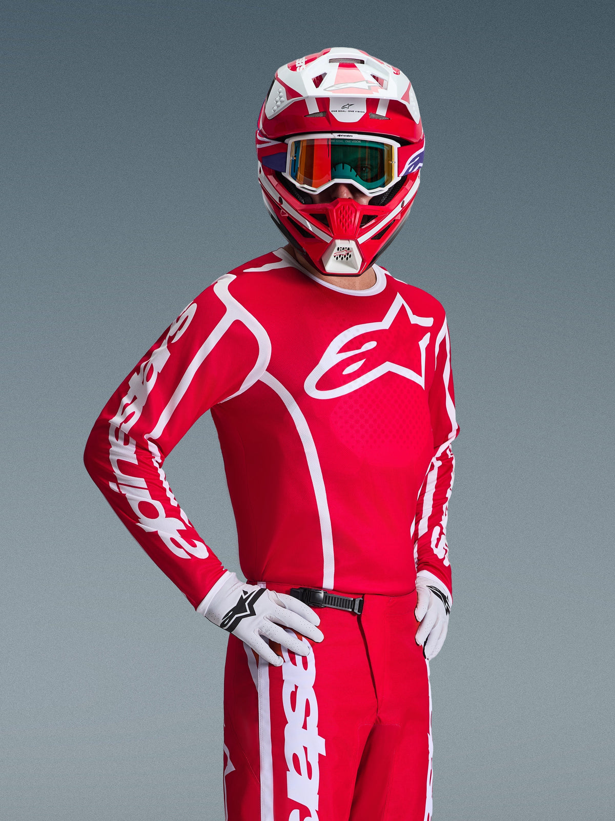 Pilote de motocross portant le maillot Alpinestars Fluid Apex 2026 rouge et blanc, casque rouge et blanc assorti avec lunettes, gants blancs et pantalon rouge, arborant des logos blancs et une coupe athlétique, tenue coordonnée pour la course tout-terrain