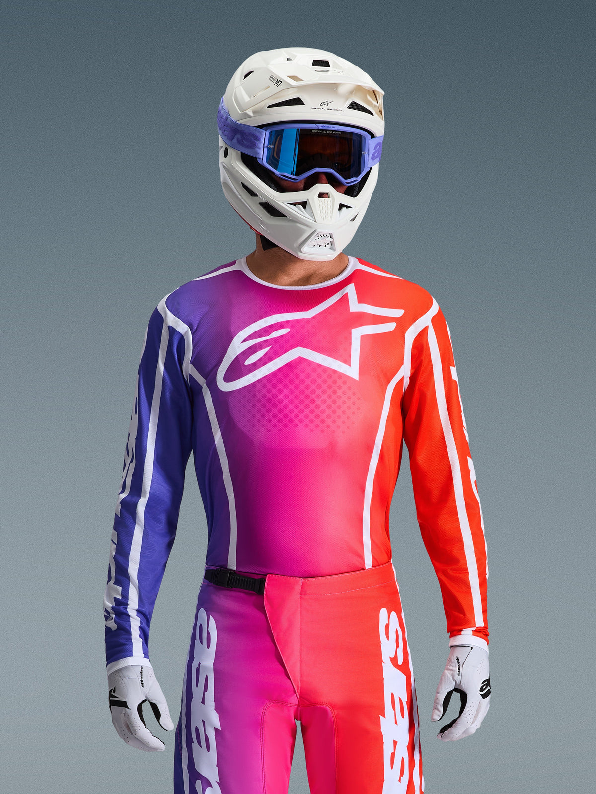 Alpinestars 2026 Fluid Apex Gear Set, Motocross-Trikot und -Hose mit einem Farbverlauf in Violett, Pink und Orange, weißes Alpinestars Stern-Logo auf der Brust, weißer Helm und lila Brille, leistungsstarke athletische Passform für den Offroad-Einsatz