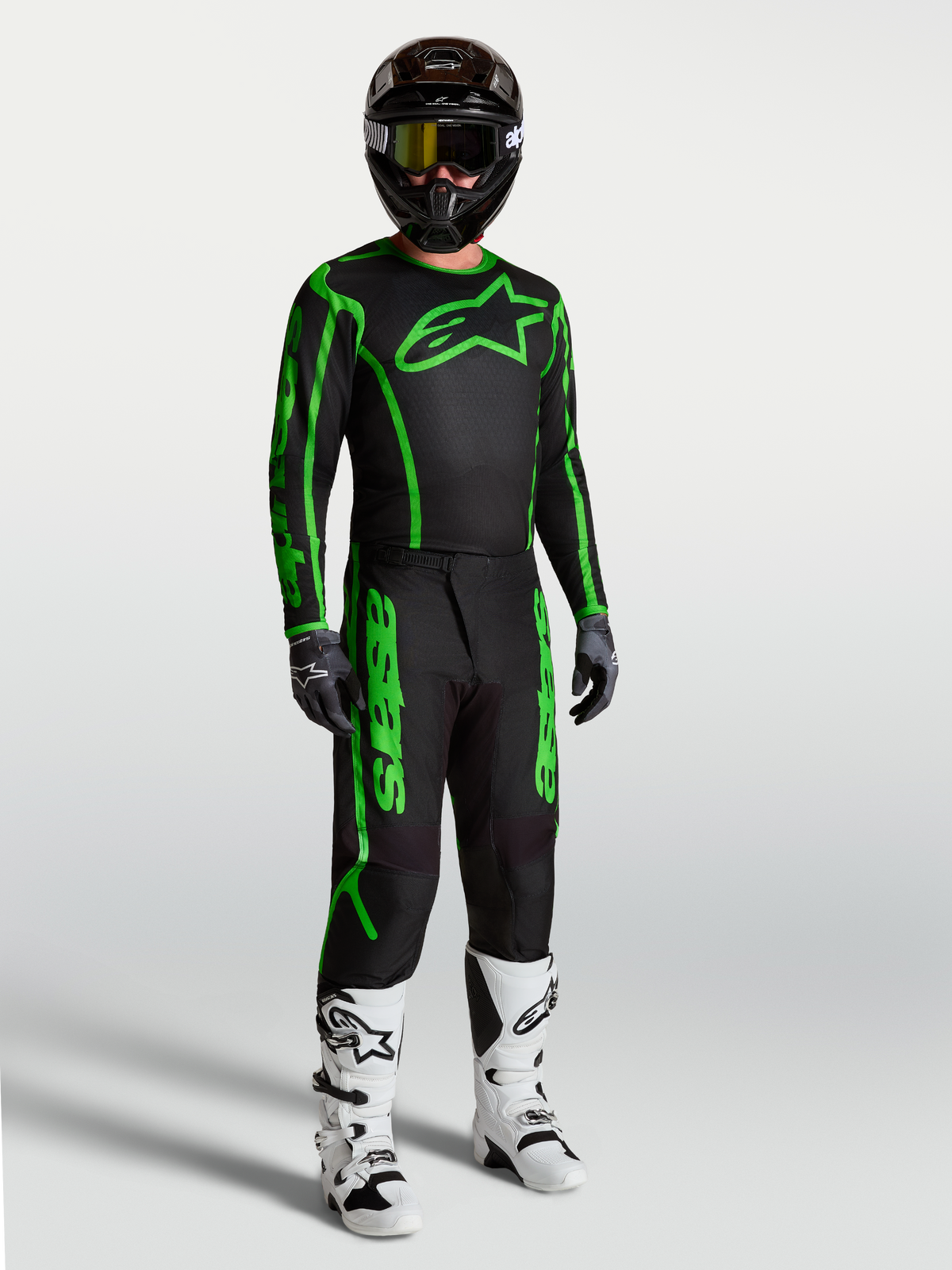 Pantalons Alpinestars Fluid Apex V2 noirs et verts fluo, équipement de motocross pour homme avec bottes blanches.