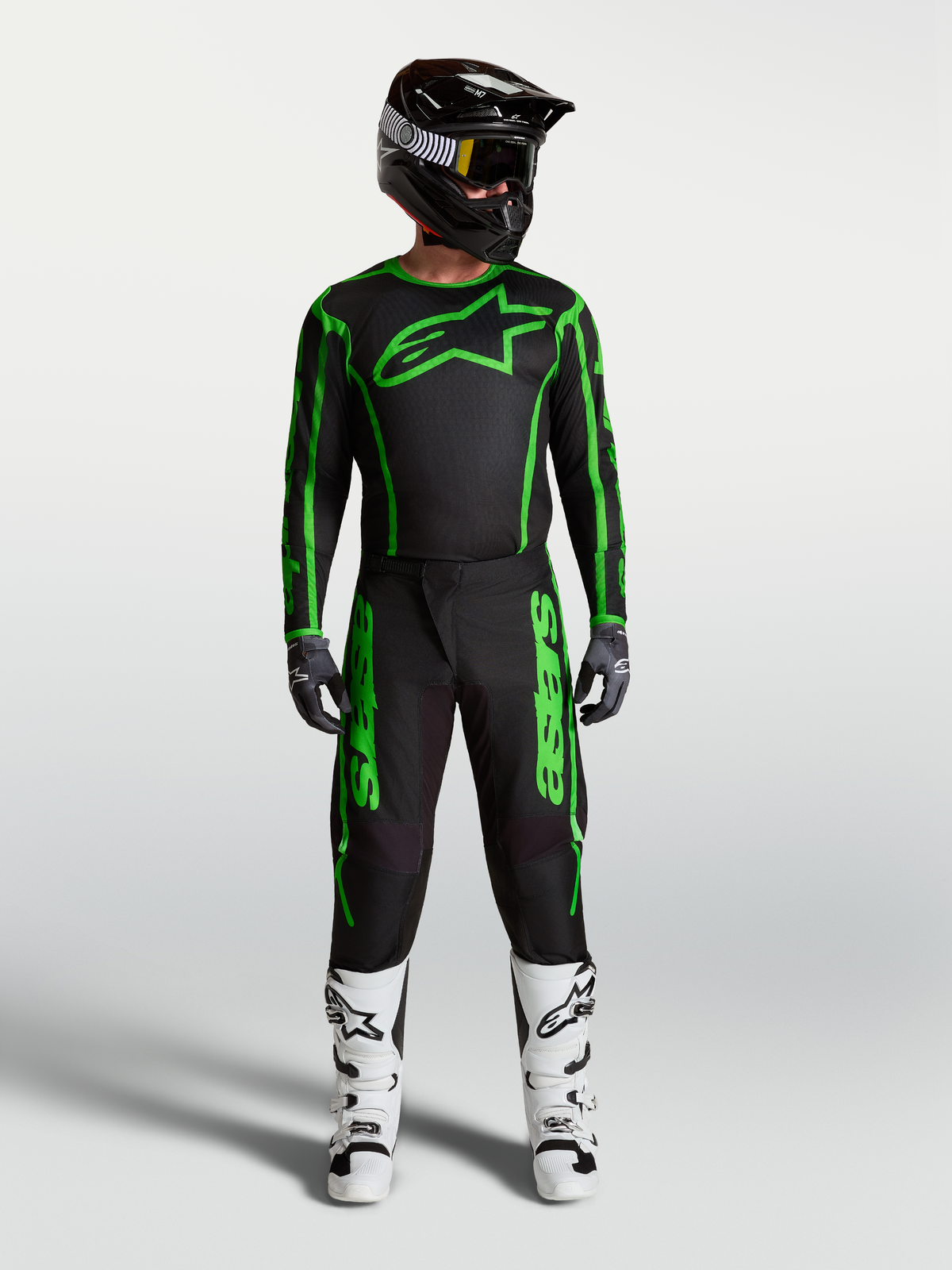 Pantalons Fluid Apex V2 Alpinestars, motocross pour homme, noirs et vert fluo, avec tenue complète et bottes blanches.