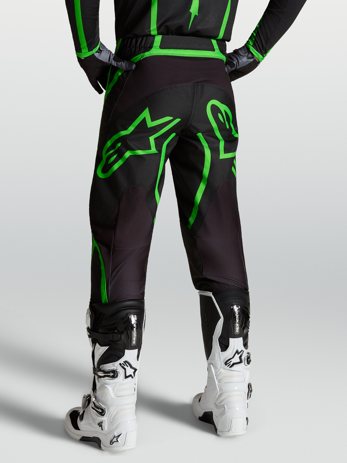 Alpinestars Pantalons Fluid Apex V2, pantalon de motocross pour homme, noir et vert fluo, vue arrière sur mannequin avec bottes blanches.