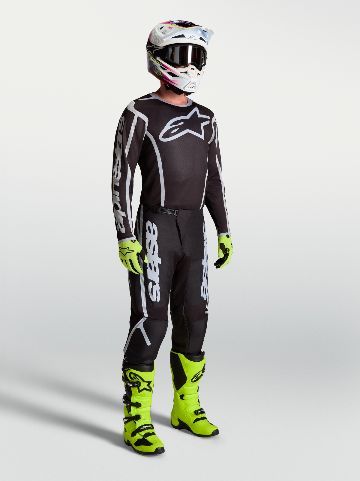 Alpinestars Fluid Apex V2 Jersey, Black and Silver motocross apparel on model with neon green boots and gloves.