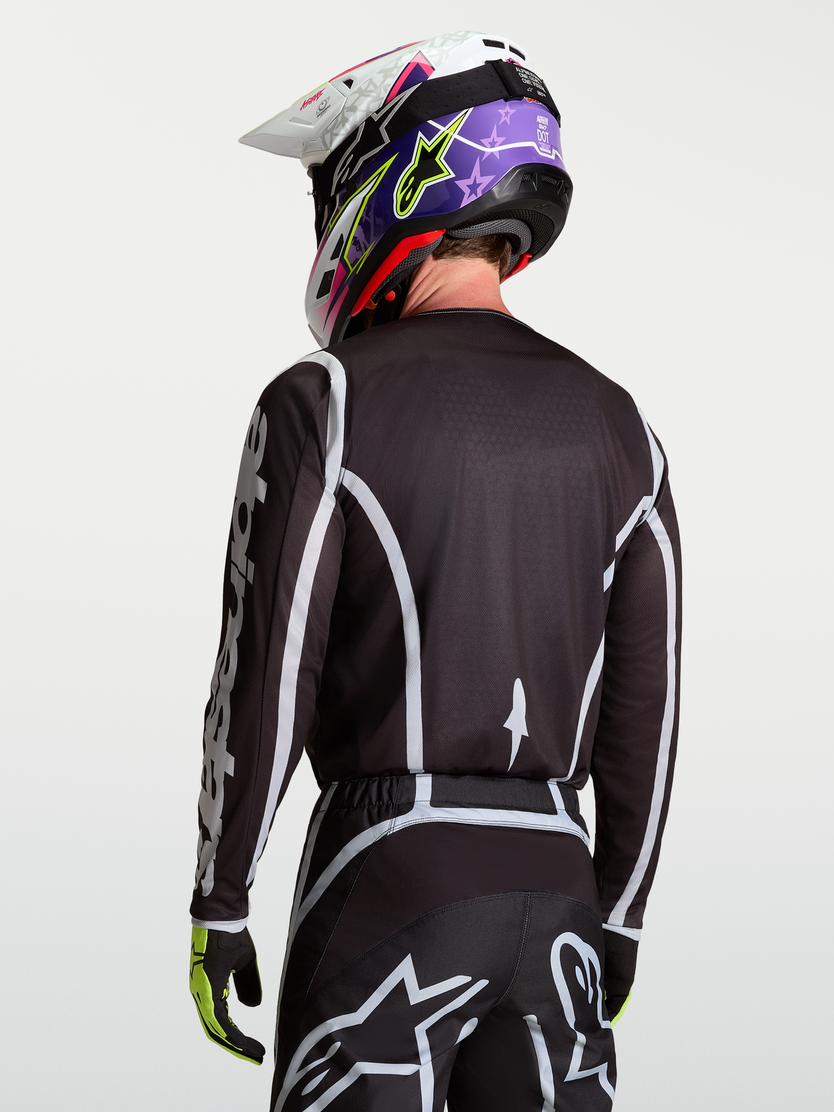 Alpinestars Fluid Apex V2 Jersey, Black and Silver motocross racing top on model viewed from the back, featuring moisture-wicking polyfabric and ergonomic cut.