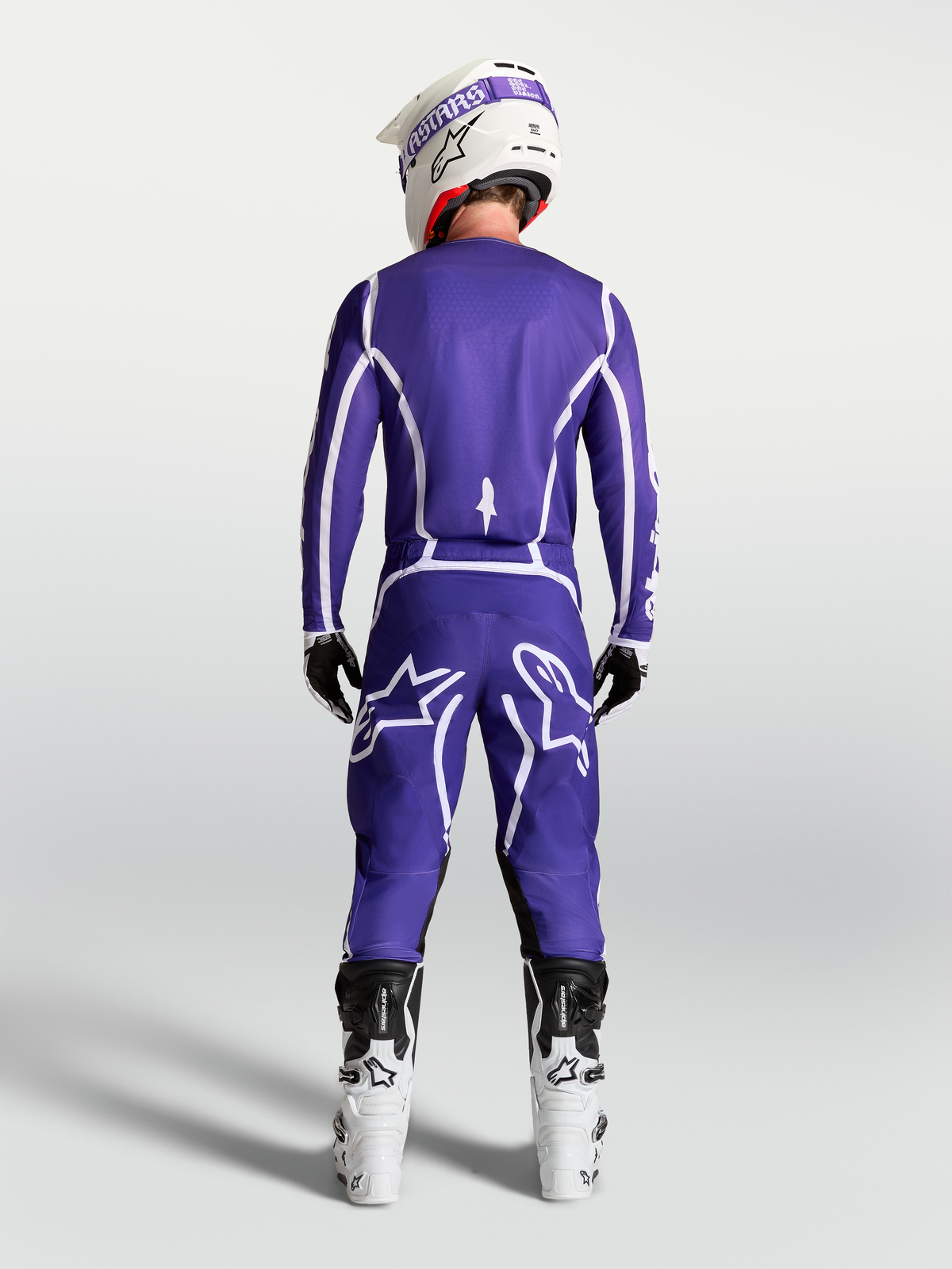 Maillot Alpinestars Fluid Apex V2, maillot de motocross tout-terrain bleu et blanc, vue de dos sur un pilote avec pantalon assorti et bottes blanches