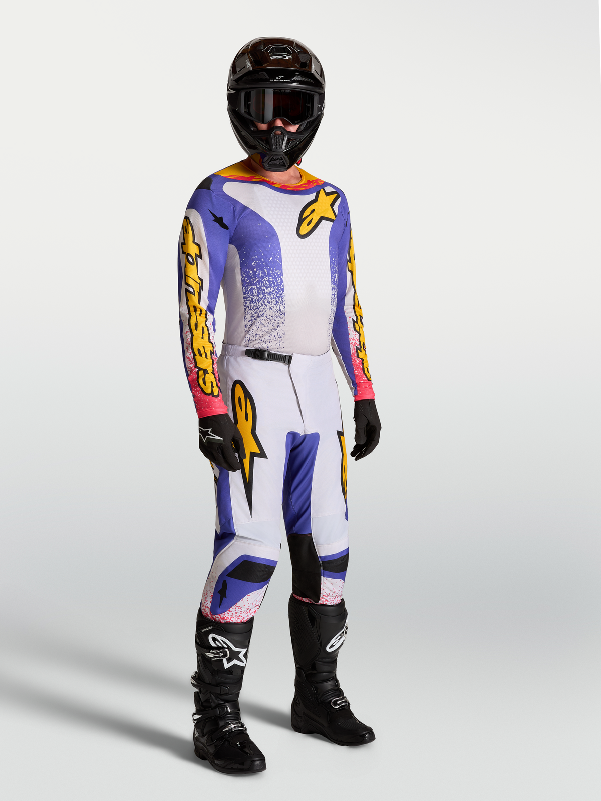 Alpinestars Fluid Drag gear set et pantalon, tenue de motocross homme, lilas, bleu et doré, porté sur mannequin.