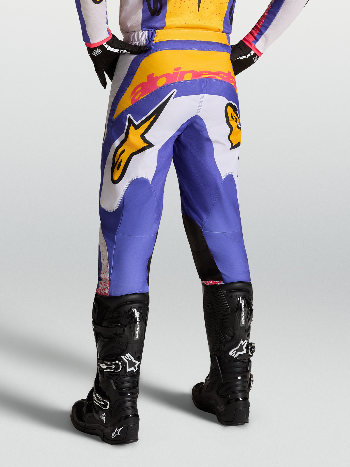 Pantalon Fluid Drag Alpinestars pour motocross, bleu et doré, jambes pré-courbées et empiècement arrière renforcé.