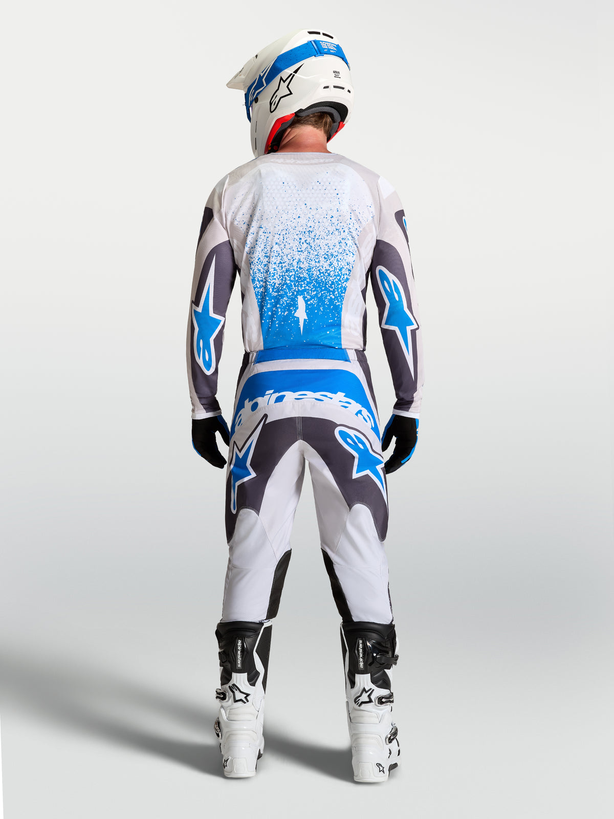 Maillot Fluid Drag Alpinestars, maillot de motocross pour homme, gris et bleu, respirant, porté de dos avec casque et bottes tout-terrain