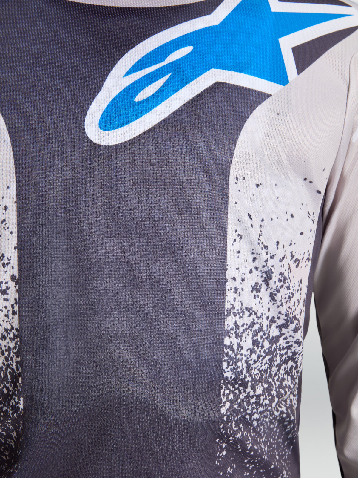 Maillot Fluid Drag Alpinestars, motocross pour homme, gris et bleu, gros plan sur le tissu respirant avec logo étoile.