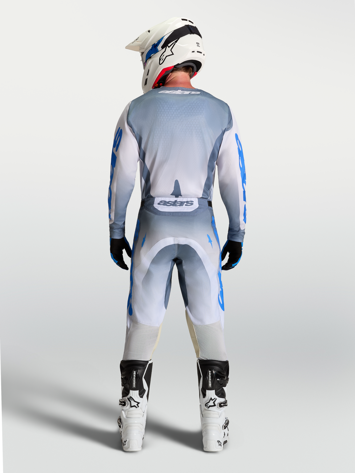 Alpinestars Racer Amber jersey, motocrossjersey voor heren, grijs en blauw, volledig achteraanzicht op model met bijpassende crossbroek en witte laarzen.