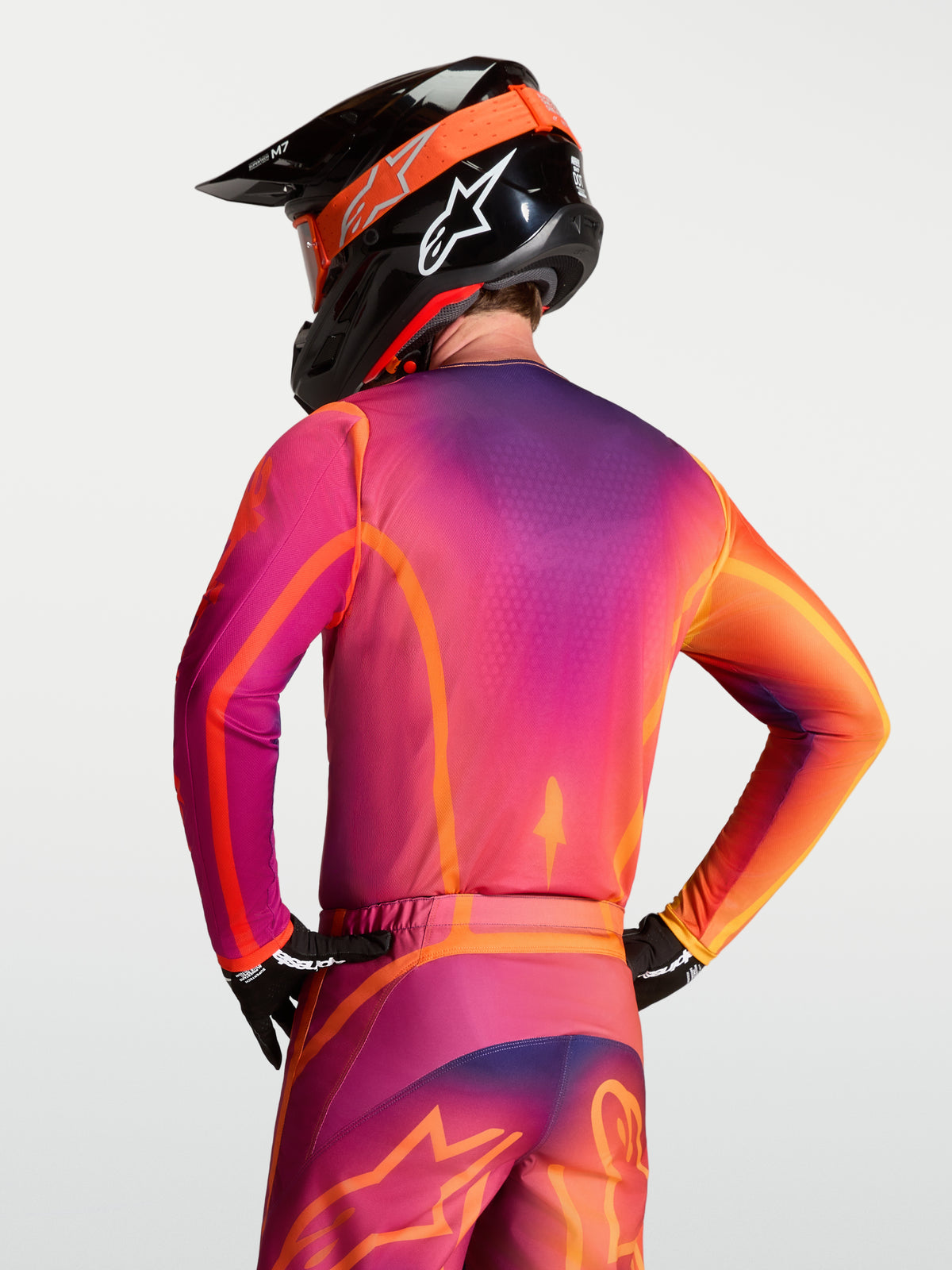 Alpinestars Fluid Kepler Jersey, purple and orange men's motocross gear, on-model rear view showing the ergonomic athletic fit.