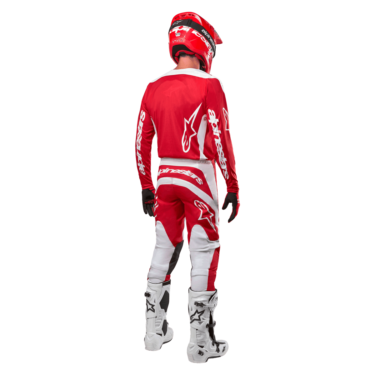 Achteraanzicht van een motorcrosser die de Alpinestars 2024 Fluid Lurv Jersey in Mars Red White draagt, gecombineerd met een bijpassende rood-witte broek, witte off-road laarzen en een rode helm, waarbij het rugontwerp en de Alpinestars-branding getoond worden.