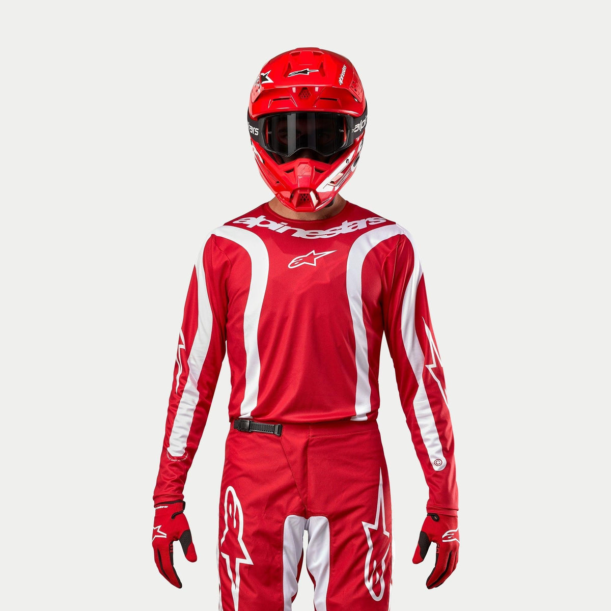 Alpinestars 2024 Fluid Lurv Jersey, motocross jersey, Mars Red en wit, gedragen met bijpassende rode broek, helm en handschoenen, met witte grafische accenten op de mouwen en opvallende branding op de borst, atletische pasvorm voor off-road racen