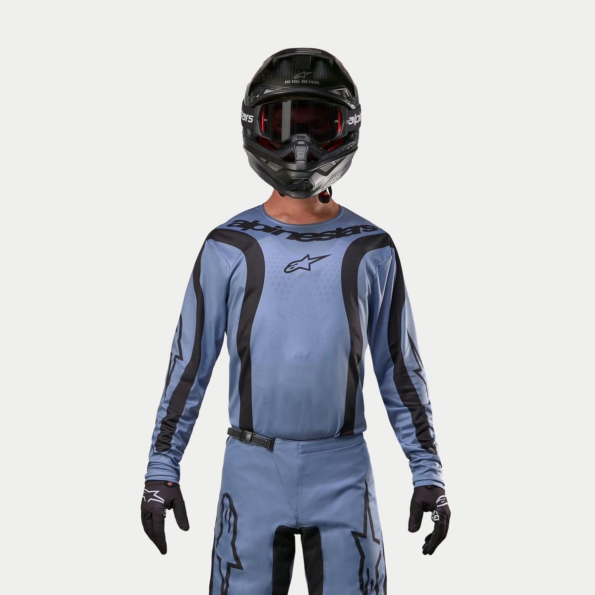 Maillot Alpinestars Fluid Lurv 2024, maillot de motocross, bleu clair et noir, porté par un pilote avec un pantalon assorti, casque noir avec lunettes rouges et gants noirs, tenue coordonnée pour la course tout-terrain