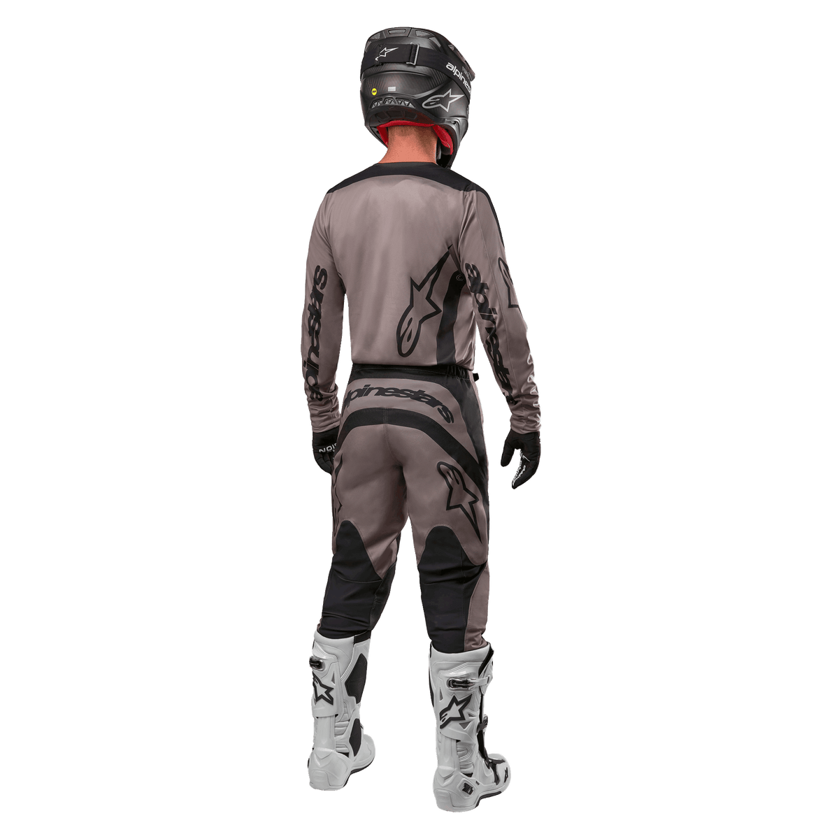 Alpinestars 2024 Fluid Lurv Jersey, motocross jersey, Mud Black, achteraanzicht van een motorcrossrijder in bijpassende race-uitrusting, zwarte helm en witte laarzen, met opvallende zwarte Alpinestars-logo's en een sportieve pasvorm voor off-road prestaties.