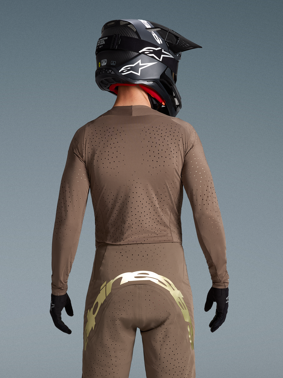 Alpinestars Limited Edition Supertech Air Gold Trikot und MX-Hose, Motocross-Ausrüstung, Herren, Braun und Gold, lasergeschnittene Belüftung, Rückansicht eines Fahrers mit Helm
