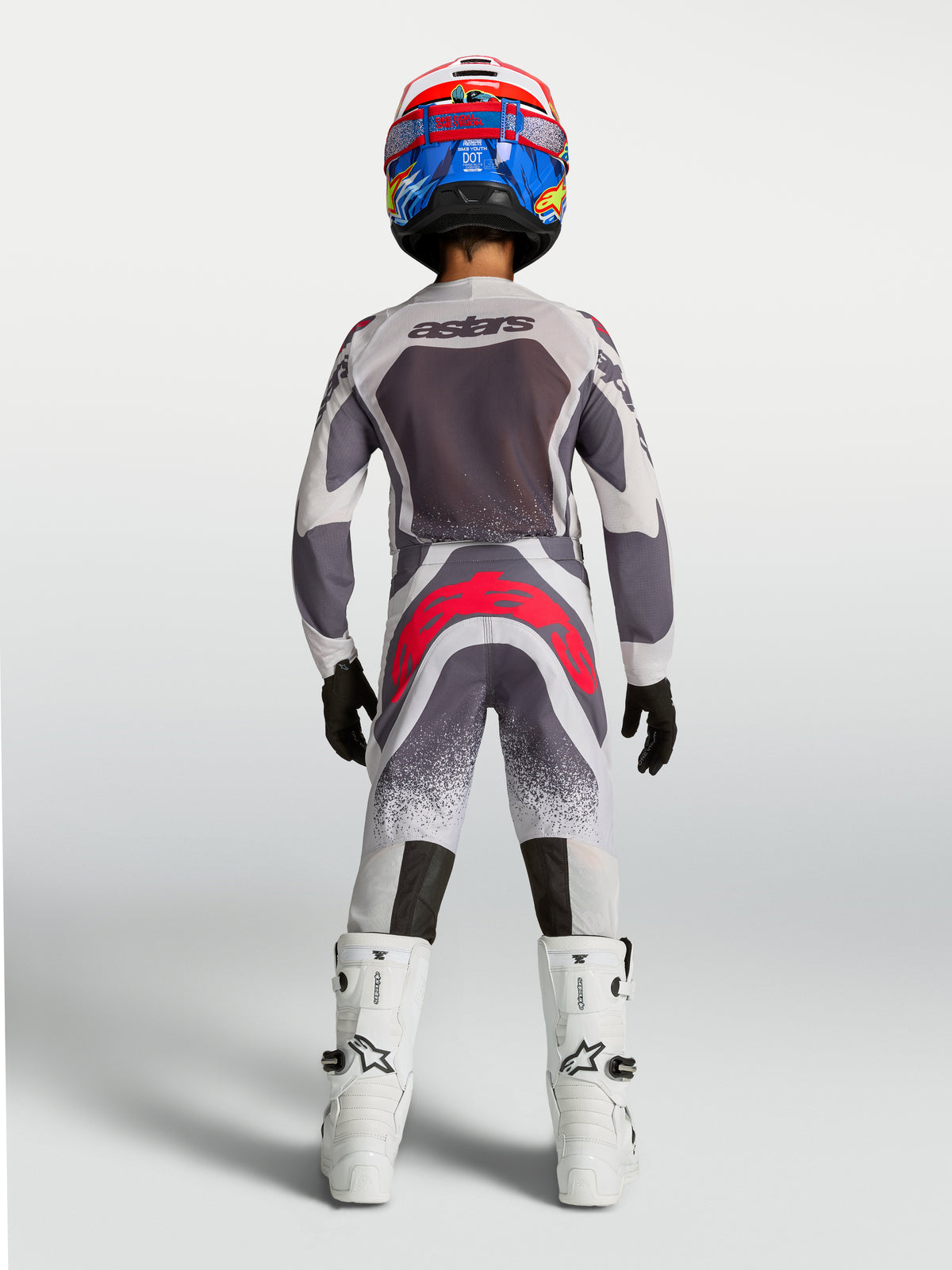 Ensemble Alpinestars Supertech Swan Junior 2027, équipement de motocross gris et blanc avec touches rouges, vue de dos.