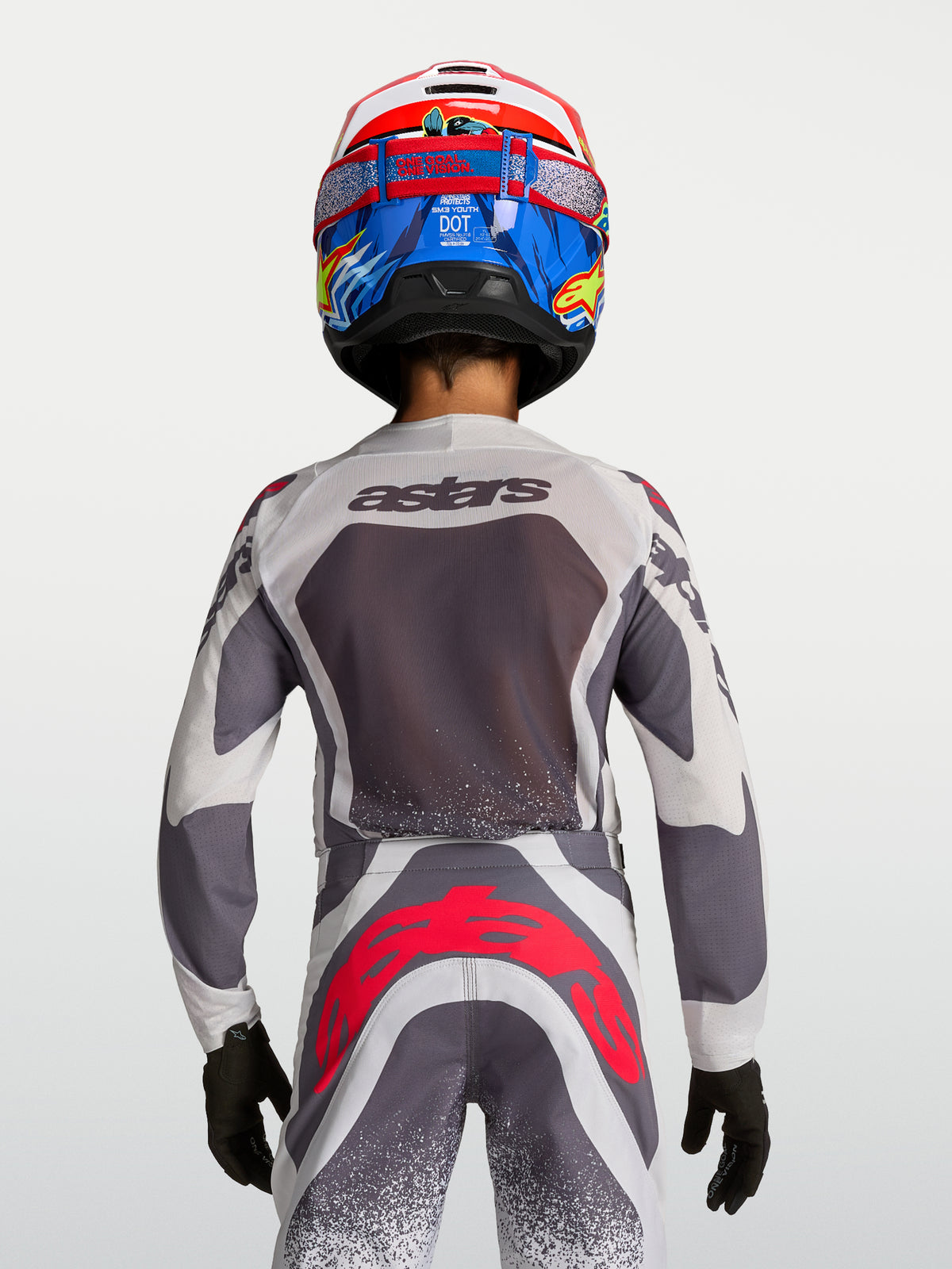 Maillot et pantalon Alpinestars Supertech Swan Junior, tenue de motocross grise et blanche avec rouge fluo, vue de dos.