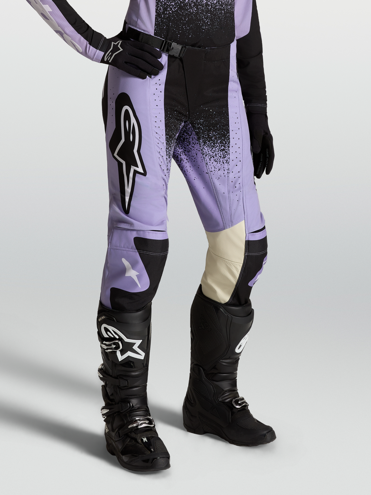 Alpinestars Stella Techstar Swan, pantalon de motocross pour femme, coloris violet et noir, porté avec des bottes et gants noirs, construction en poly-tissu durable et cuir aux genoux pour une performance tout-terrain optimale