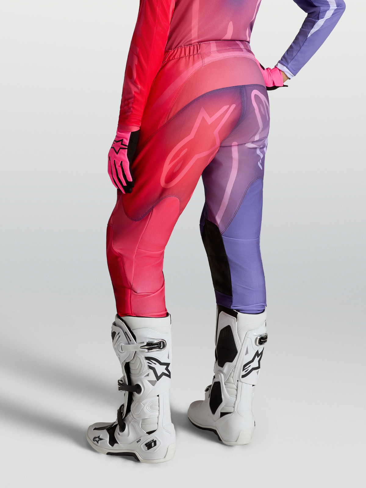 Pantalon Stella Fluid Kepler d'Alpinestars, pantalon de motocross pour femme violet et rouge, jambes préformées avec empiècement stretch, porté avec des bottes de moto Tech 10 blanches