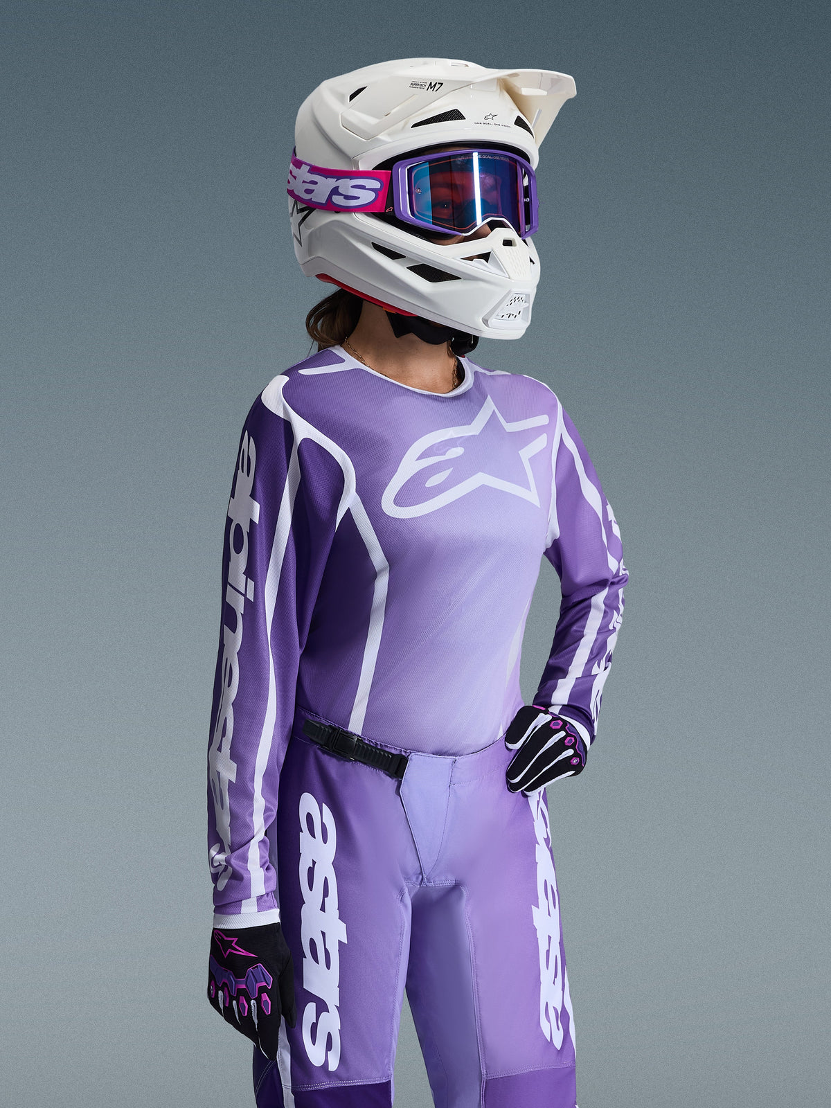 Alpinestars 2026 Stella Fluid Apex Gear Set voor dames, motorcross outfit, paars en wit shirt met Alpinestars-logo's, bijpassende paarse broek, witte helm met paarse bril en zwart-paarse handschoenen, professionele off-road race-uitrusting