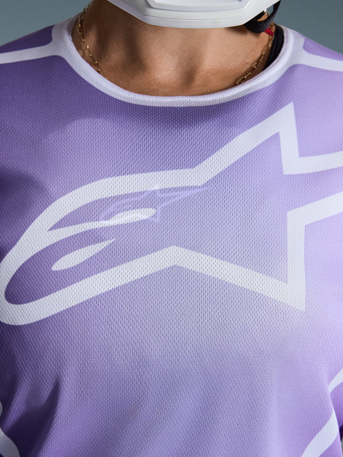 Alpinestars 2026 Stella Fluid Apex Jersey, close-up van de borst, paars met witte graphics, groot wit Astars-logo op mesh polyfabric constructie