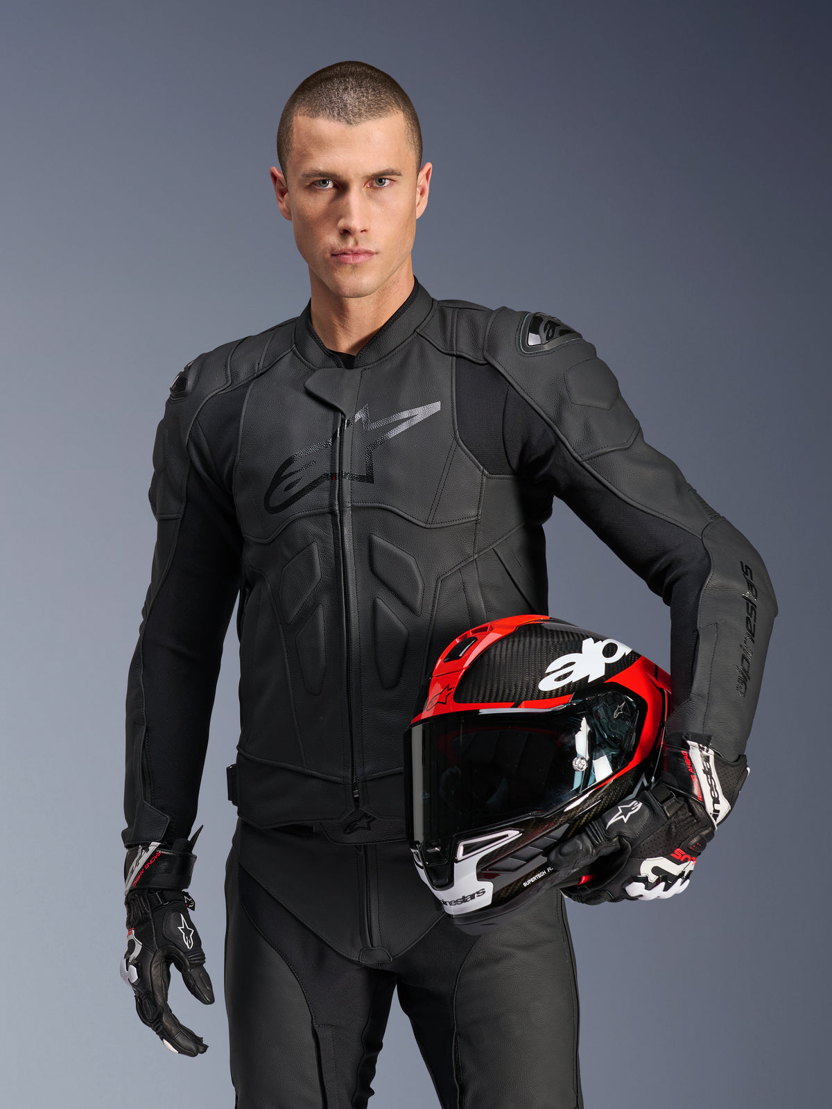 Alpinestars Dusk Lederjacke, schwarze Herren-Motorradjacke mit Nucleon PLASMA Protektoren und rotem Helm.
