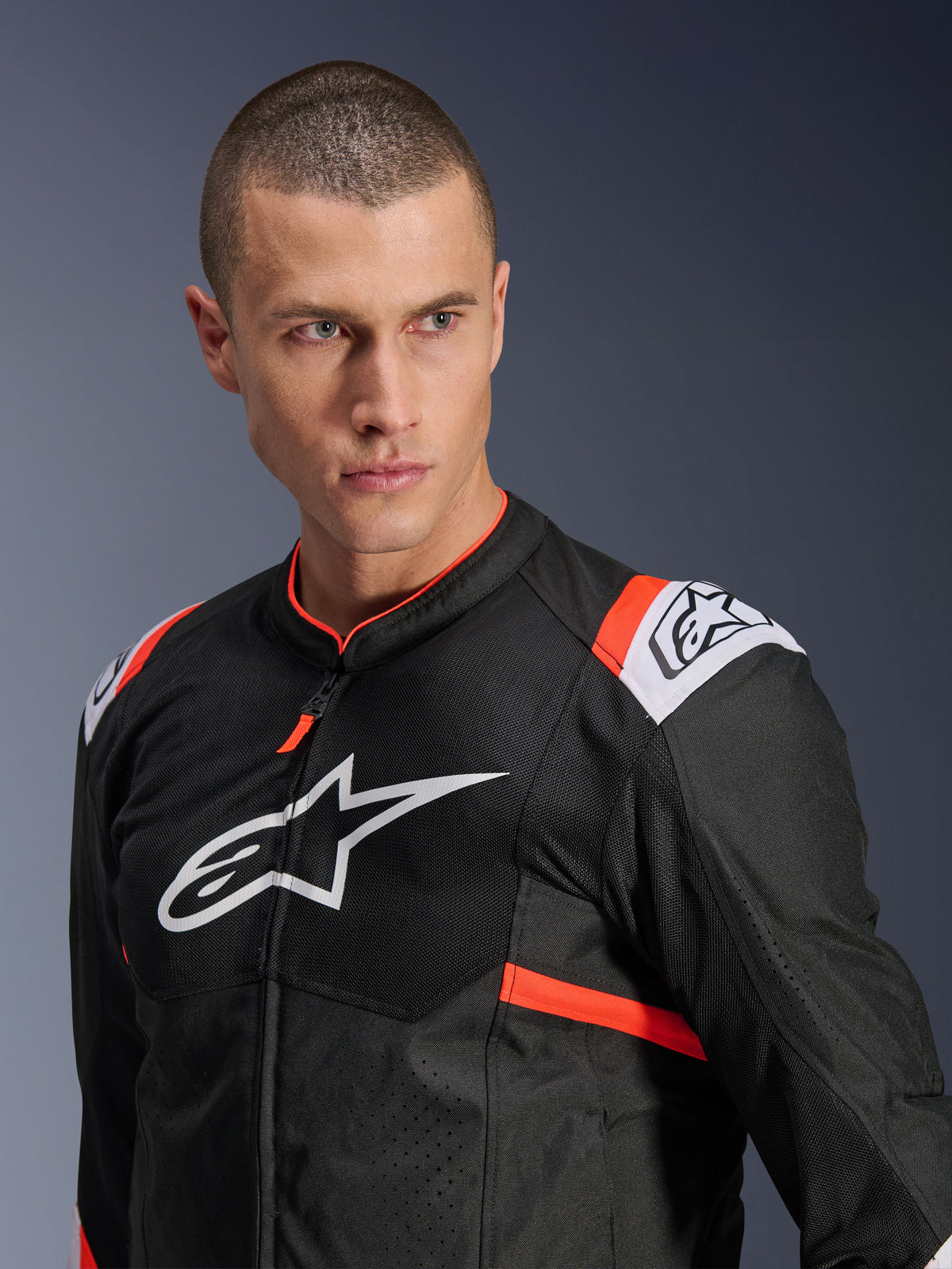 Veste Alpinestars T-SPS Air v2, noire avec accents blancs et rouge fluo, construction en textile mesh pour la circulation de l'air, grand logo Alpinestars blanc sur la poitrine, portée par un mannequin, style de conduite sport urbain