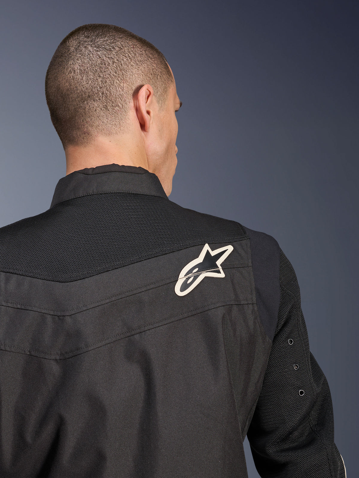 Alpinestars T-Dyno Air Jacke, schwarze Textil-Motorradjacke, Nahaufnahme der Rückansicht mit Fokus auf die atmungsaktive 3D-Mesh-Passe und Ärmel, weiß-schwarzes Stern-Logo auf der rechten Schulter.