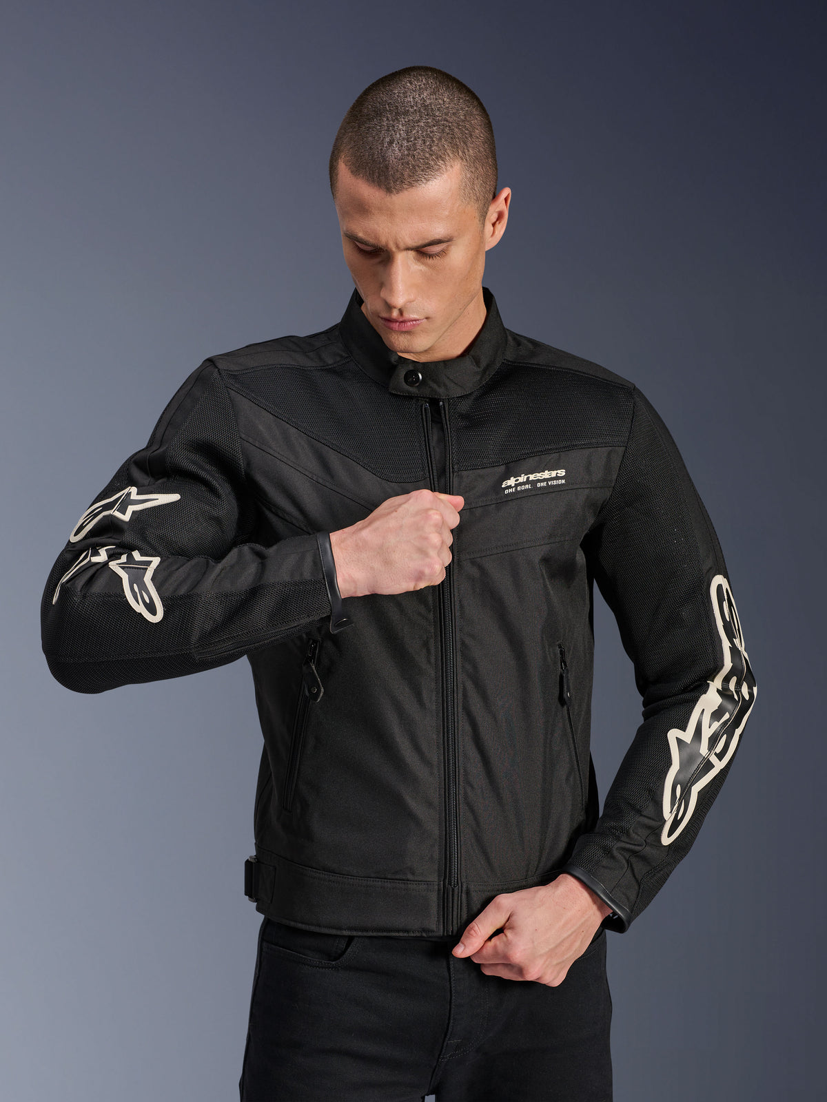 Alpinestars T-Dyno Air Jacke, Schwarz, Textil-Motorradjacke mit 3D-Mesh-Einsätzen und weißen Logos an den Ärmeln, getragen von einem Model beim Schließen des Frontreißverschlusses, urbaner Street-Riding-Stil