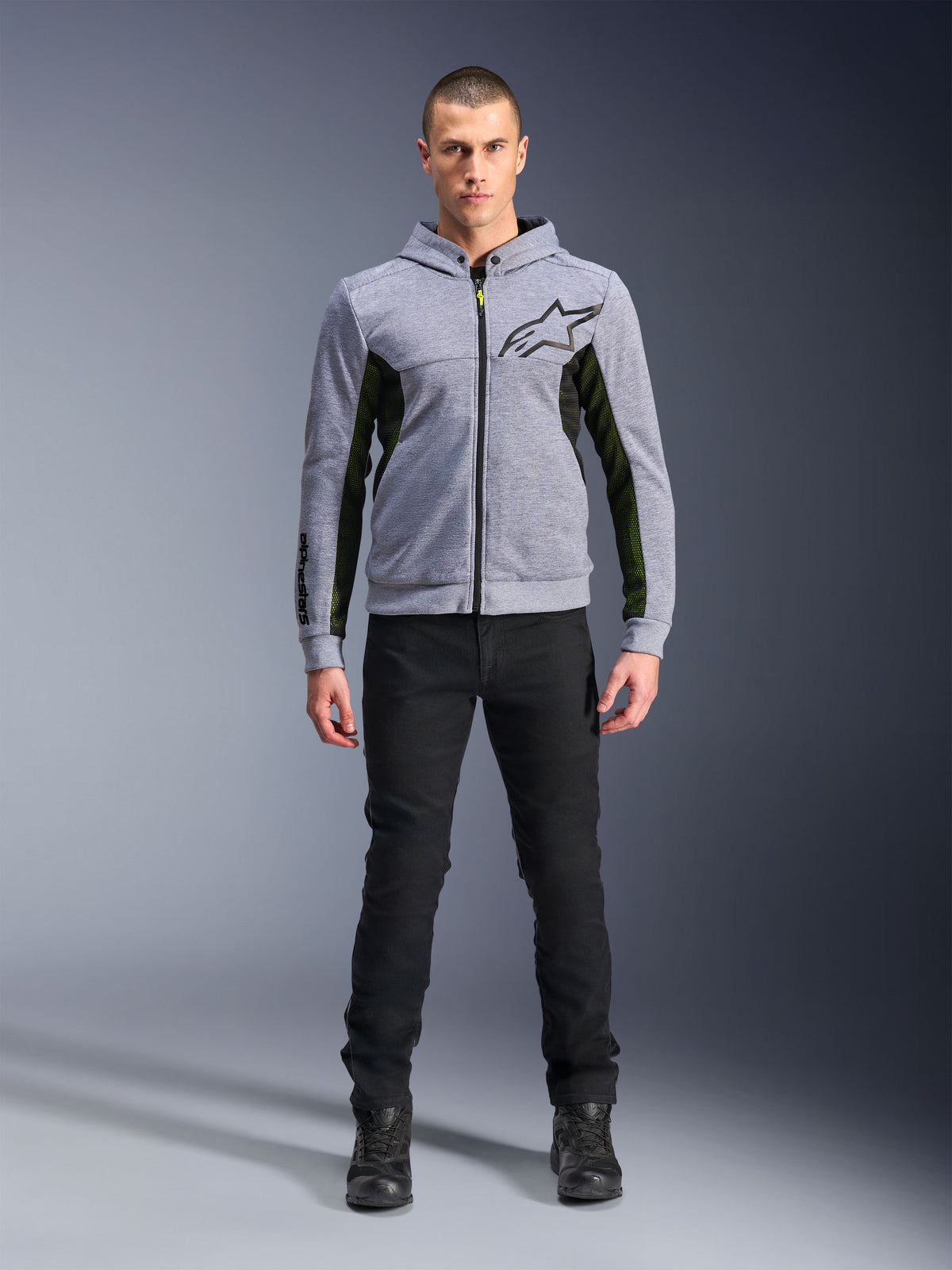 Alpinestars Chrome Air Sport Hoodie, Gray Heather Black, technical motorcycle hoodie with black mesh side panels and neon yellow accents, black star logo on chest, worn with black pants and boots, modern urban riding style.