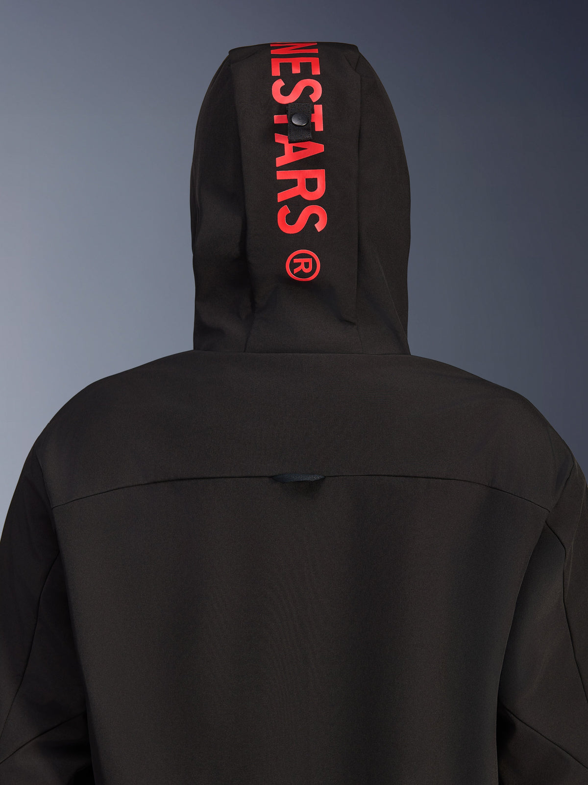 Alpinestars Radium Tech Hoodie, urban motorjas, zwart met felrood, achteraanzicht gefocust op de capuchon met verticale rode logo-branding, winddichte textiele shell en eigentijds ontwerp.