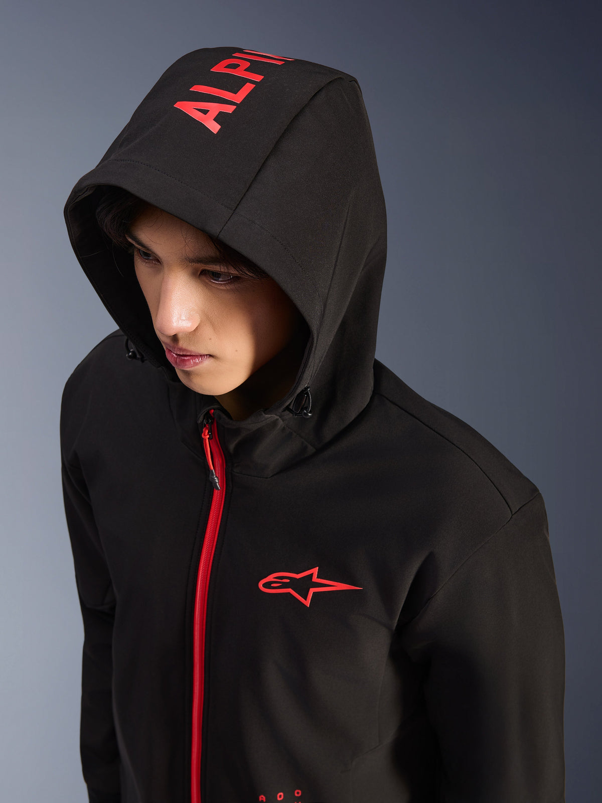Alpinestars Radium Tech Hoodie, zwart en felrood, stedelijke technische shell motorhoodie, rood Alpinestars-logo op de borst en rode branding op de capuchon, felrode rits, moderne op motorsport geïnspireerde streetwear