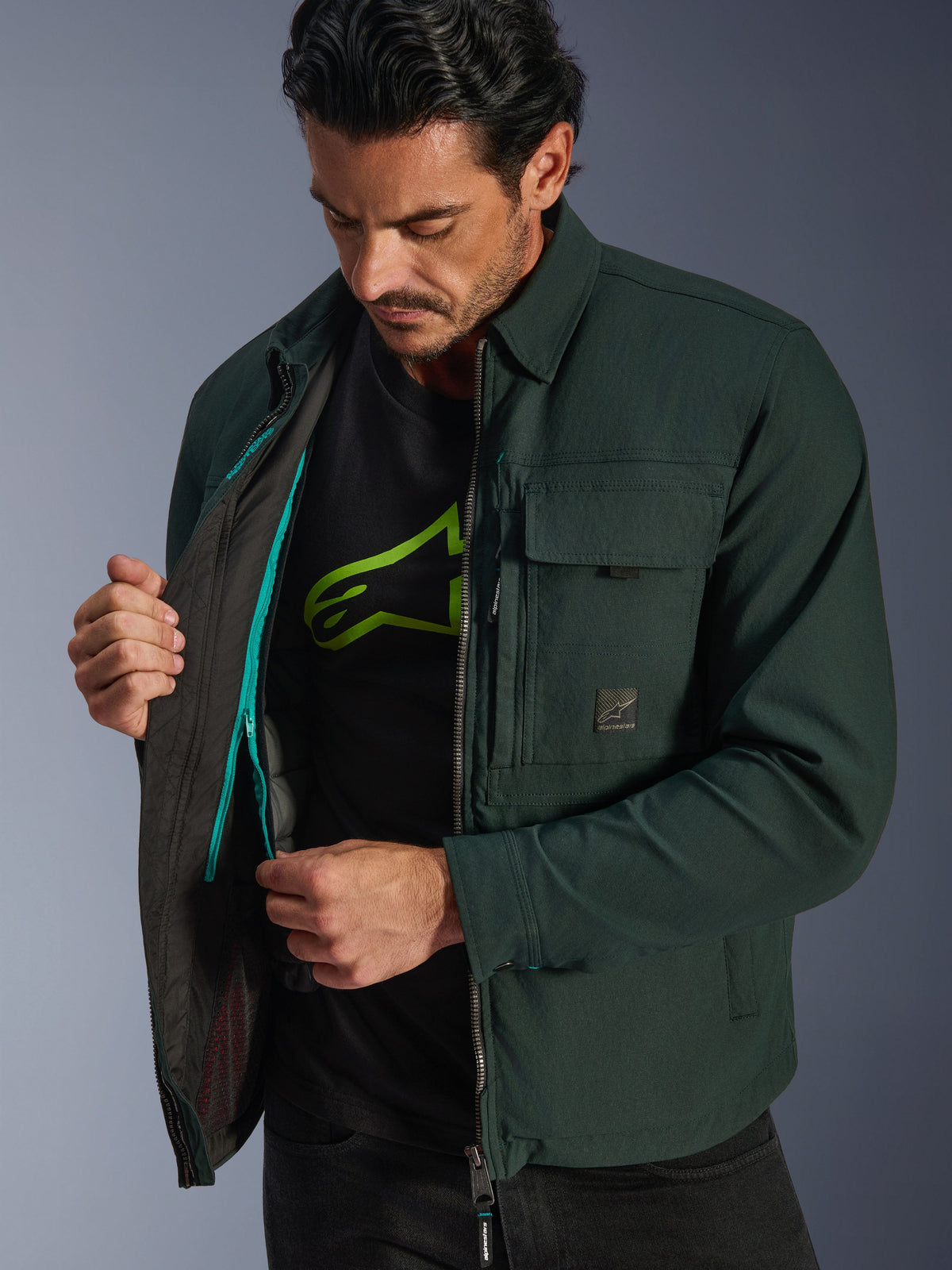 Alpinestars Bryon Water Resistant Overshirt, Dark Emerald, lifestyle-weergave van model die het thermische binnenvest en teal ritsdetail laat zien, stedelijke motorjas van gewaxt canvas met cargozakken